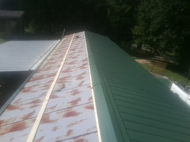 Old rusted panels beside newly installed green metal roofing — Wind Damage Roof Repair by Roofing Brothers in Mission Hills