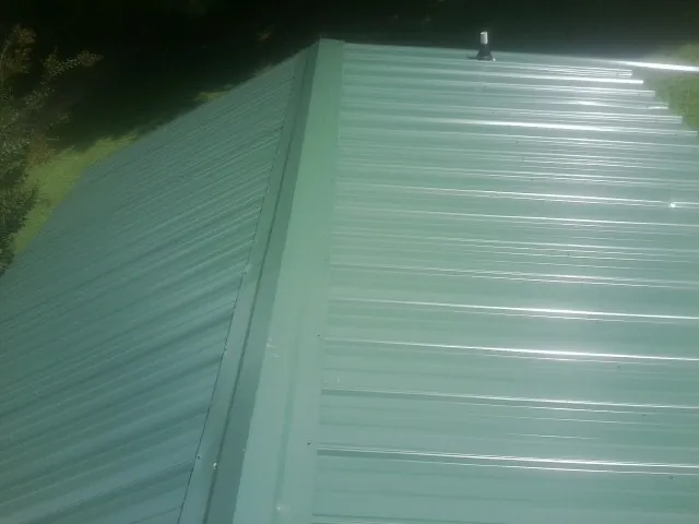 New green metal panels meeting at the ridge of a roof — Flat Roof Repair work by our crew in Mission Hills