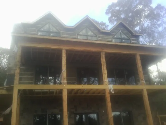Dormers and porch framing on a large log home under construction — Roof Coating work by our crew in Mission Hills
