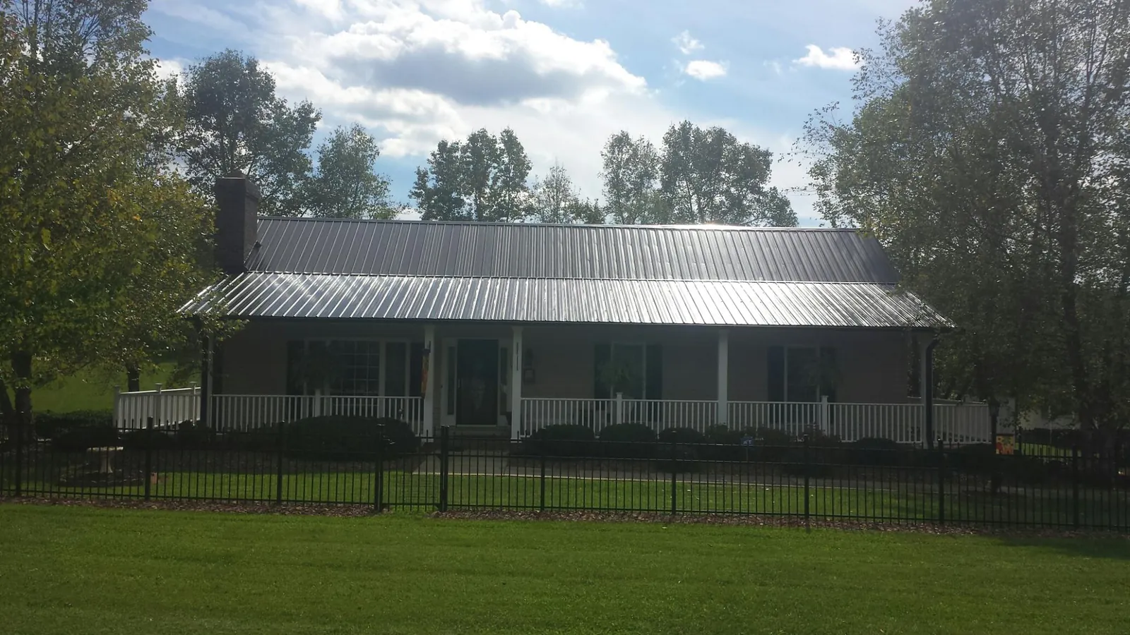 Gray metal roof on a brick ranch with a full width front porch — Gutter Guard Installation work by our crew in Mission Hills