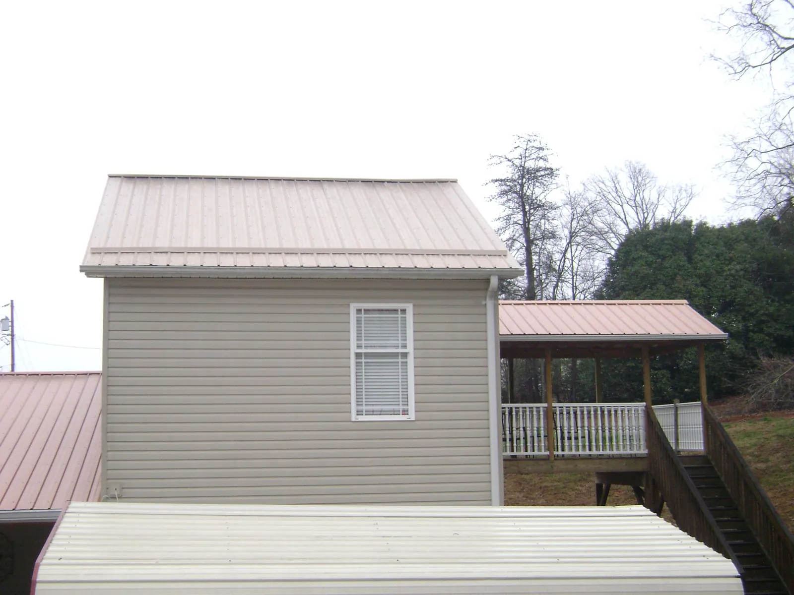 Tan metal roofs on a two story addition and attached porch, from a Roof Replacement job in Mission Hills