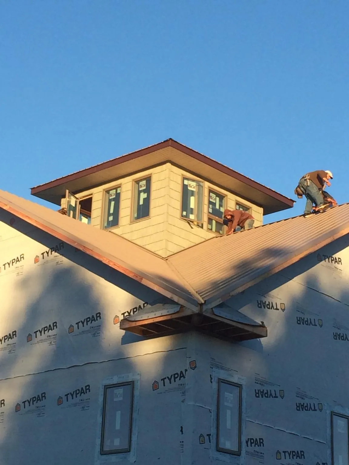 Roofers working around a rooftop cupola on a new metal roof at sunset — Roof Waterproofing in Mission Hills by Roofing Brothers